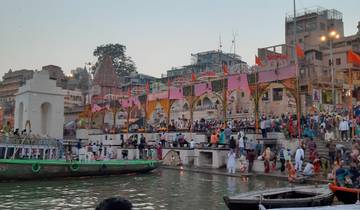 A vibrant riverside with colorful decorations and crowds of people.