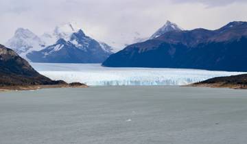 Snow-capped mountains and a glacier reaching a lake.