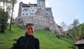 Woman posing in front of a castle on a hill.