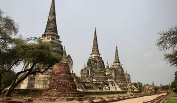 Ancient temple ruins with spires and trees surrounding it.
