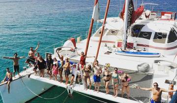 Group posing on a catamaran in the ocean.