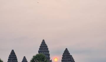 Sunset view of Angkor Wat with the sun between the temple towers.