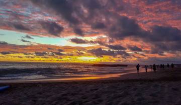 Vibrant sunset over a beach with people and surfers