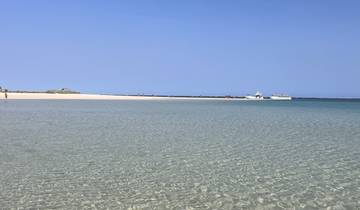 Shallow clear turquoise water with boats in the distance.