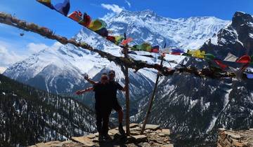 Two people standing on a viewpoint with mountains.