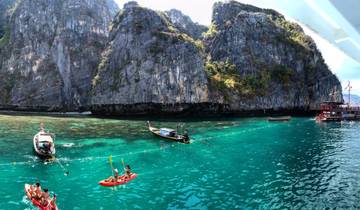 Boats floating near large limestone cliffs; people kayaking in the area.