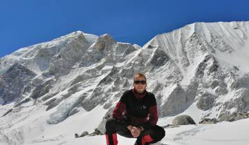 Person in a snowy mountainous landscape, posing in front of rugged mountains.