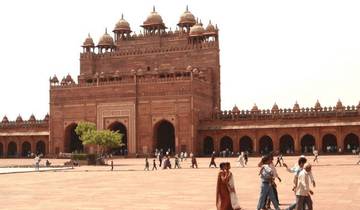 People walking in a large courtyard in front of a historic building.