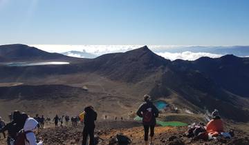 Hikers overlooking mountain lakes with clouds below.