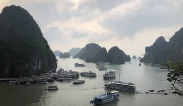 Numerous boats on the water with limestone karsts landscape.