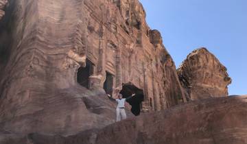 Person posing in front of ancient rock-cut architecture.
