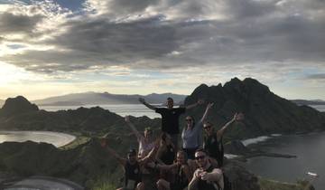 Group of people on a hilltop with scenic views of a bay and mountains.