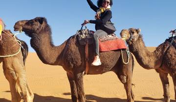 Person riding a camel in the desert with a smile.