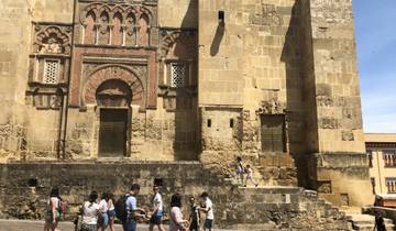 Historical building wall with intricate carvings, people walking nearby.