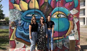 Three women standing in front of a colorful mural.