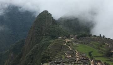 Panoramic view of Machu Picchu with lush greenery and mist.