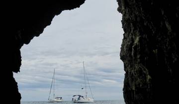 View from inside a cave with the sea and sailboats visible.