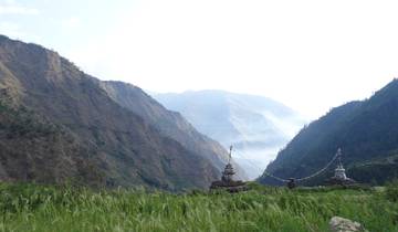 Green field with stupas and mountains in the background.