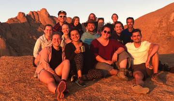 A group of people sitting on a rock during sunset.