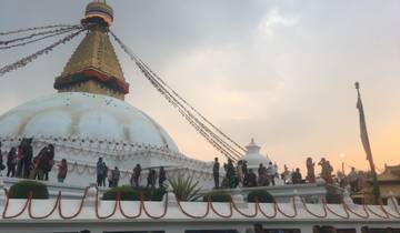 A large stupa surrounded by people, during sunset.
