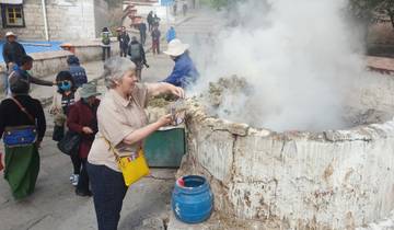 People gathered around a steaming structure outdoors.