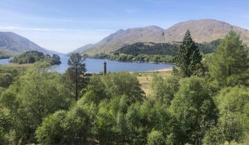 Scenic view of a lake surrounded by mountains and trees.