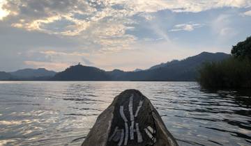 Canoe on a lake with mountainous backdrop at dusk.