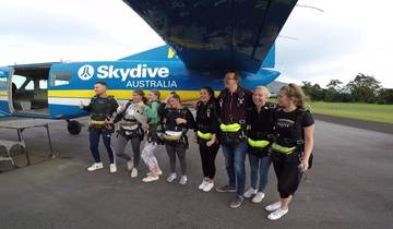 A group of people in skydiving suits near a plane.