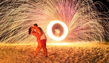 Couple kissing on the beach with a fire show.