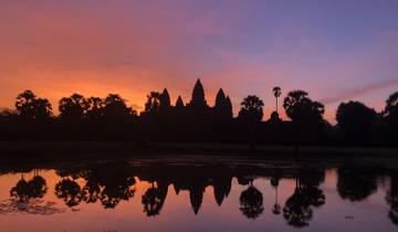 Sunset view of Angkor Wat reflected in water.