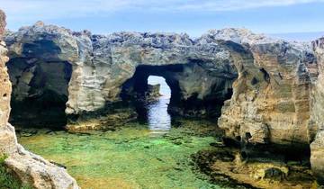 Rocky formations with natural arches over clear water.