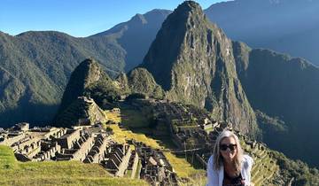 A woman posing with a view of the ancient ruins of Machu Picchu.