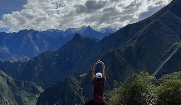 Individual with arms raised facing mountain range.
