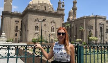 Person standing in front of historic mosque with twin minarets.