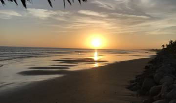 Sunset over the ocean with a sandy beach.