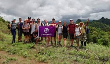A group of hikers posing with a flag in a mountainous area.
