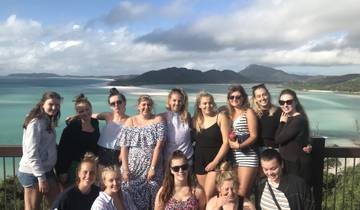 Group of people posing in front of ocean and mountains.