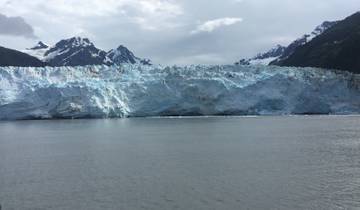 A glacier with a backdrop of mountains and cloudy sky.