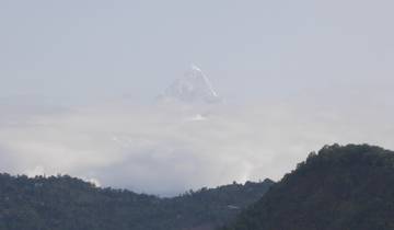 Mountain peak rising above clouds with clear skies.