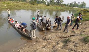 Tourists boarding wooden boats on a riverbank.