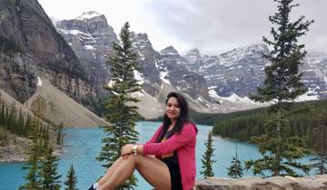 Woman posing with mountainous landscape and turquoise lake.