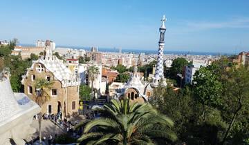 View of Park Güell with colorful architecture and a city skyline.