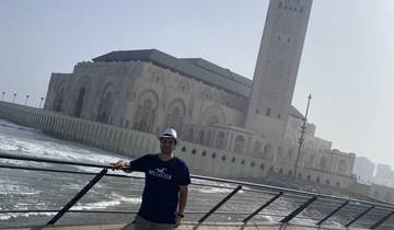 A person posing near a large mosque or building.