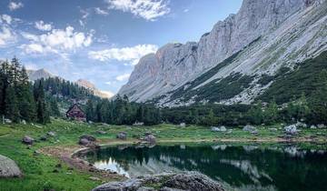 A tranquil mountain lake with a chalet and rugged peaks.