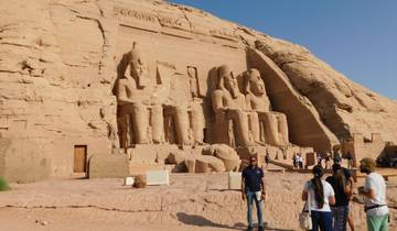 Large stone statues at the entrance of a temple, with people around.
