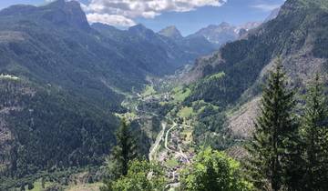 Panoramic view of a valley with lush greenery and winding roads.