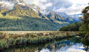 Scenic view of a mountain landscape with a reflective lake in the forefront.