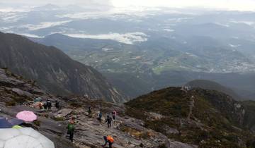 View from a high point showing hikers on a rocky path with a panoramic landscape.