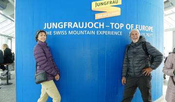 A couple at Jungfraujoch, the Top of Europe sign with a mountainous backdrop.