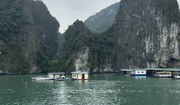 Boats on the water with towering rocks and greenery.